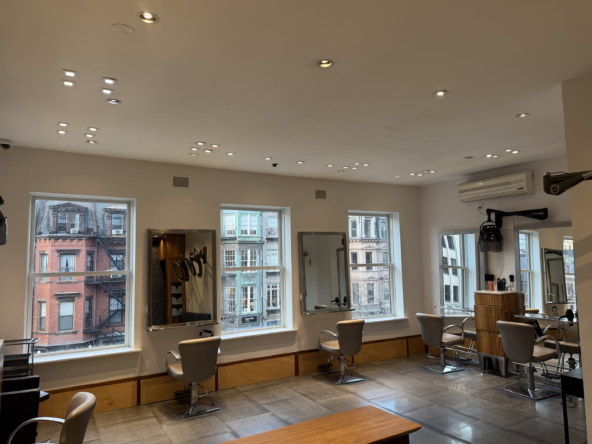 Bright, spacious salon with multiple styling stations and urban city view, ideal for salon renters.
